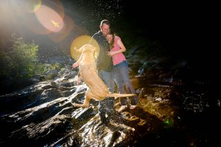 A newly engaged couple plays with their dog down by the river in Pollock Pines, CA