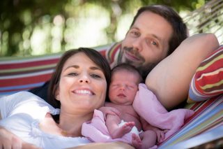 A couple and their first daughter spending time on the hammock in Granite Bay, California.