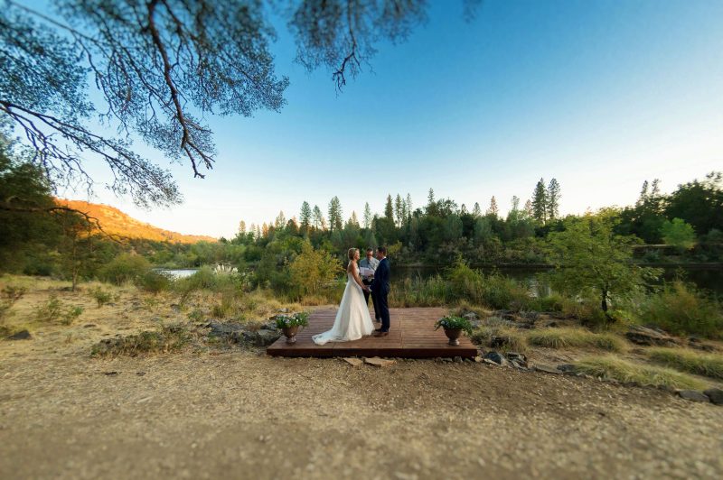 A couple exchanges their vows in the late afternoon light along the riverside in Coloma, California.