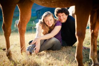 A farm couple peers through the legs of their horse during their Fausel Ranch engagement session.