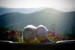 Long-married couple sits on bench overlooking mountains