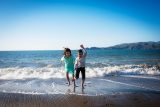 Brother and sister laughing playing in the water on the beach